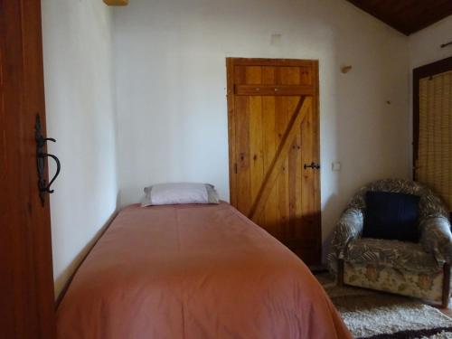 a bedroom with a bed and a chair and a door at New Village in Vila Nova da Baronia