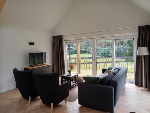 a living room with a couch and chairs and a television at De Eekhoorn in Ugchelen