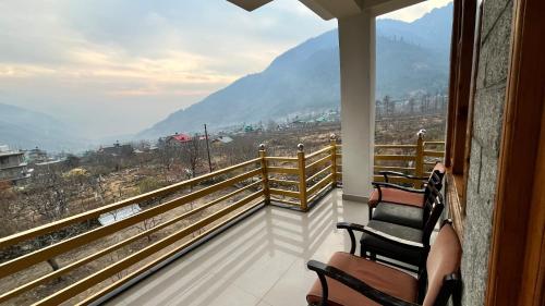 a balcony with two chairs and a view of a mountain at Wander Thrives iNN in Manāli
