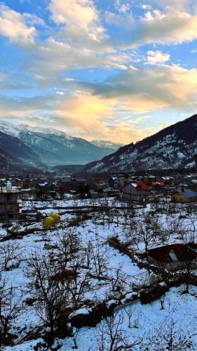 a snowy field with a town and mountains in the background at Wander Thrives iNN in Manāli