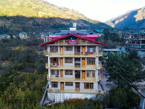 a tall building with a red roof in a city at Wander Thrives iNN in Manāli