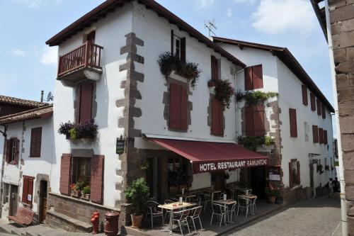 a white building with tables and chairs in front of it at Hostel Ramuntcho in Saint-Jean-Pied-de-Port