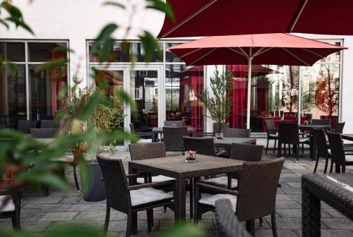 an outdoor patio with tables and chairs and umbrellas at Ramada by Wyndham Essen in Essen
