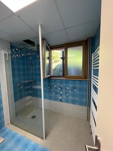 La salle de bains est pourvue d'une douche et de carrelage bleu. dans l'établissement Aux balcons des xettes, à Gérardmer