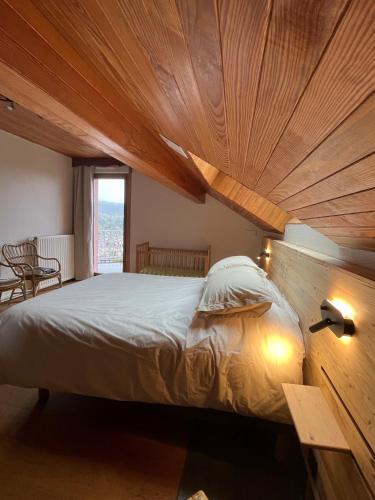 une chambre avec un grand lit avec un plafond en bois dans l'établissement Aux balcons des xettes, à Gérardmer