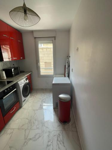 une cuisine avec des armoires rouges et un micro-ondes dans l'établissement Appartement calme et cosy, à Sèvres