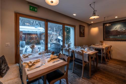 a dining room with tables and chairs and a window at Sonnmatten Boutique Hotel & Apartments Zermatt in Zermatt