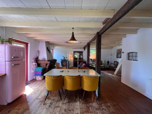 a table with yellow chairs in a living room at Privé huisje op unieke groene plek in Den Dolder