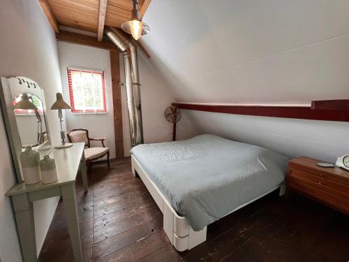 a small bedroom with a bed and a desk at Privé huisje op unieke groene plek in Den Dolder