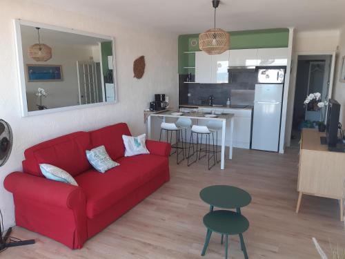 un salon avec un canapé rouge et une cuisine dans l'établissement superbe appt face à la mer, wifi, à Canet