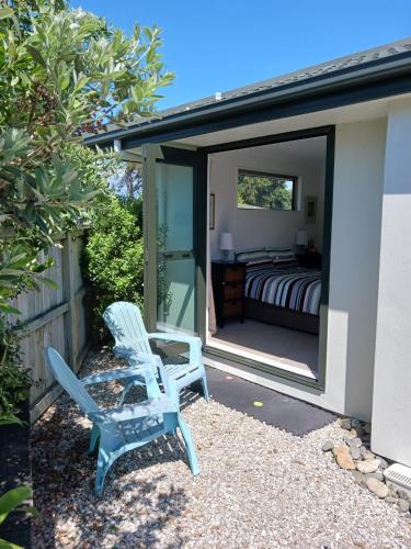 two blue chairs and a bed in a bedroom at Doonside Private Cottage at Grossi Point Reserve in Mapua