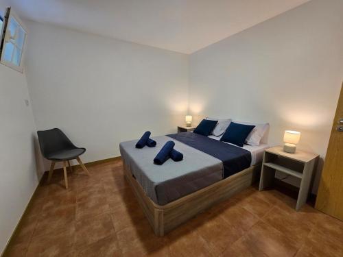 a bedroom with a bed with blue pillows and a chair at Autonomia House II in Câmara de Lobos