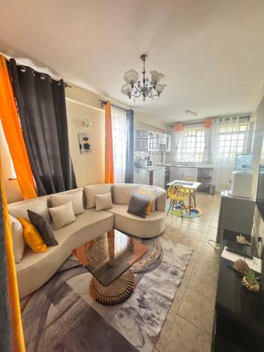 a living room with a white couch and a kitchen at Queen Sheba Luxury homes in Kisumu