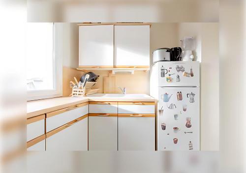 Il comprend une cuisine équipée d'un réfrigérateur blanc avec de nombreux aimants. dans l'établissement Chambre privée à Lille centre, à Lille