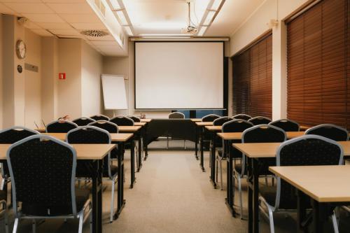 an empty classroom with tables and chairs and a whiteboard at Economy Silesian Hotel in Katowice