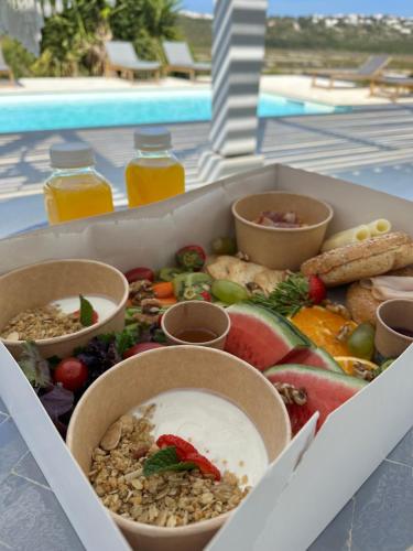 eine Kiste mit verschiedenen Lebensmitteln neben einem Pool in der Unterkunft Herdade d'Amoreira Jasmin Villa in Aljezur