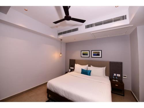 a bedroom with a white bed with a ceiling fan at Belvedere Suites in Greater Noida