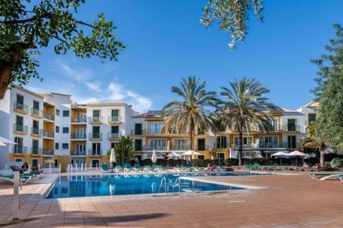 a resort swimming pool with palm trees and buildings at Casa das Marés by east ALgarve guest in Tavira