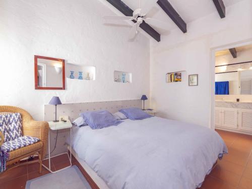 una camera con letto, sedia e ventilatore a soffitto di Villa Es Cantell a Binisafua