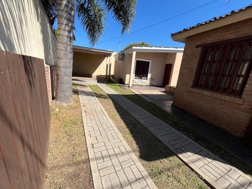 a brick sidewalk next to a house with a palm tree at Chalet Los Aromos in Embalse