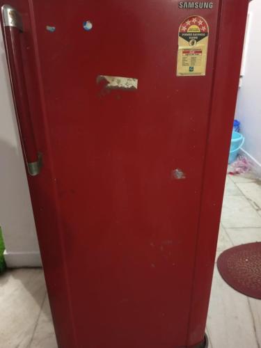 an old red refrigerator with a sticker on it at New Dev Homestay in Prayagraj