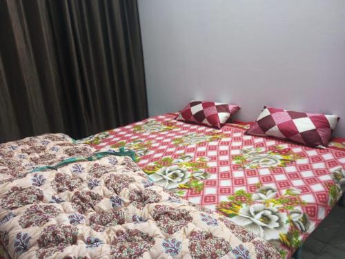 a bed with a quilt and two pillows on it at New Dev Homestay in Prayagraj