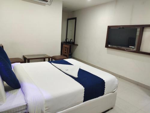 a bedroom with a bed and a tv on the wall at Hotel SkyLand in Warangal