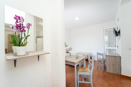 a living room and dining room with a table and purple flowers at Villaggio Residence Emmesse in Mandaradoni