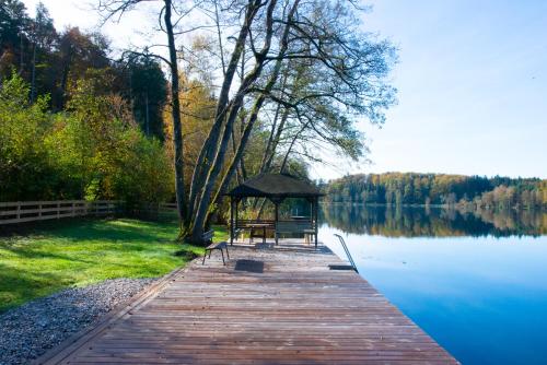 a wooden boardwalk with a gazebo next to a lake at Seehof direkt am See in Seeleiten