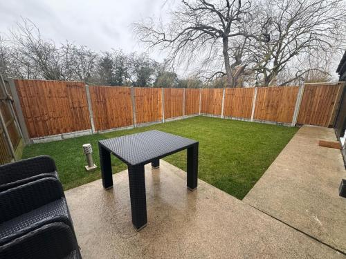 a black table in a backyard with a fence at Private cinema studio guest house with garden in Brentwood