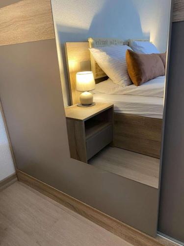 a mirror reflecting a bedroom with a bed and a nightstand at Къща за гости Плами in Tryavna