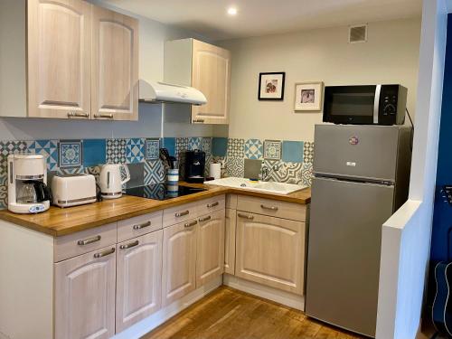  La cuisine est équipée de placards blancs et d'un réfrigérateur. dans l'établissement La Petite Escale, à Saint-Nazaire