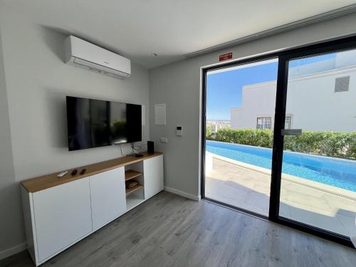 a living room with a tv and a sliding glass door at Albufeira Stylish 2 With Pool by Homing in Albufeira
