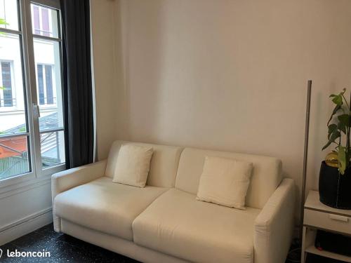 - un canapé blanc dans le salon doté d'une fenêtre dans l'établissement Le Cosy Parisien - Canal Saint Martin - Paris 10eme, à Paris