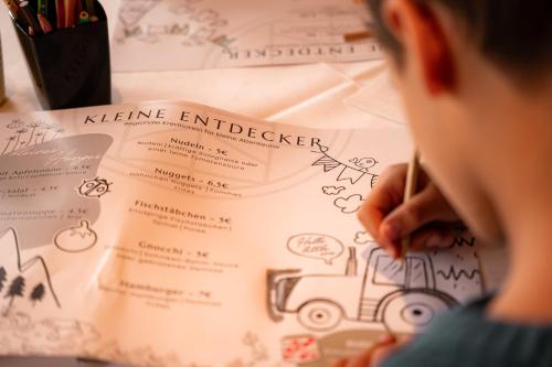 a boy writing on a piece of paper at Marienhöh - Hideaway & Spa in Langweiler