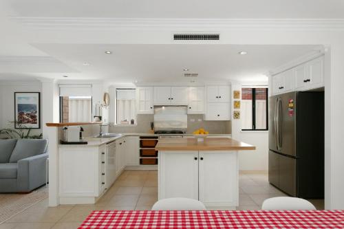 a kitchen with white cabinets and a black refrigerator at Entire Home Steps to Sorrento Beach in Perth
