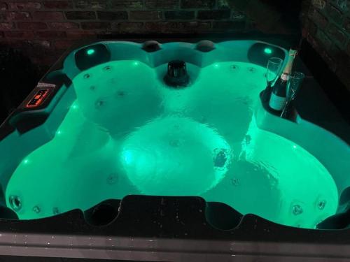 a green bath tub with a glass of wine in it at Burtree Country House, Tipi's, Treehouse & Lodge & house rooms with hot tubs in a private garden in Thirsk