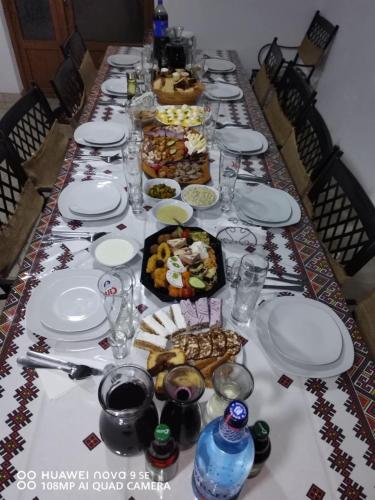 Una mesa larga cubierta con platos y cuencos de comida. en Poiana Creasta Cocosului-Casa Papadie, en Breb