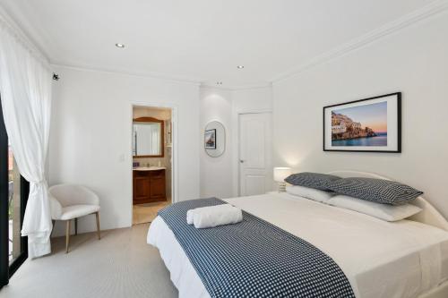 a white bedroom with a bed and a bathroom at Entire Home Steps to Sorrento Beach in Perth