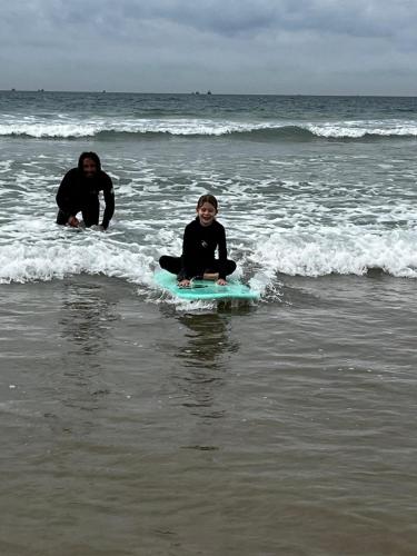 a man and a child sitting on a surfboard in the ocean at Moroccan Boho Surf House in Agadir