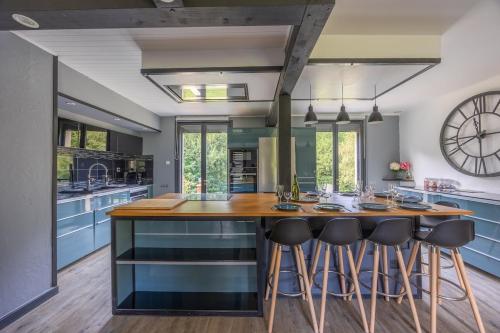 a kitchen with blue cabinets and a large kitchen island with bar stools at Peaceful house - SPA - Babyfoot - Forest in Ablon