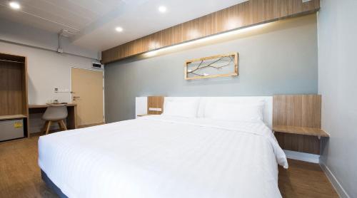 a bedroom with a large white bed and a desk at Shade House - Bitec Bangna in Bangkok