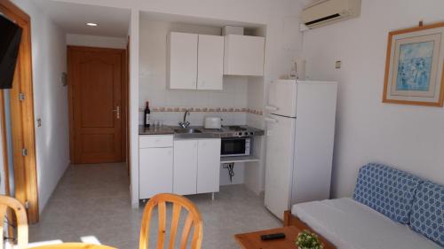a kitchen with white cabinets and a couch and a table at Mar y Paz by Youroom in Can Picafort