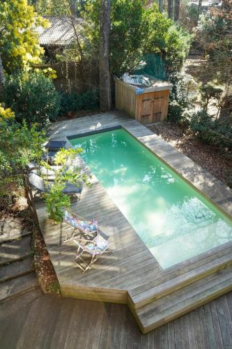 - une piscine avec une terrasse et une chaise dans l'arrière-cour dans l'établissement La Villa Tropicool, à Lège-Cap-Ferret