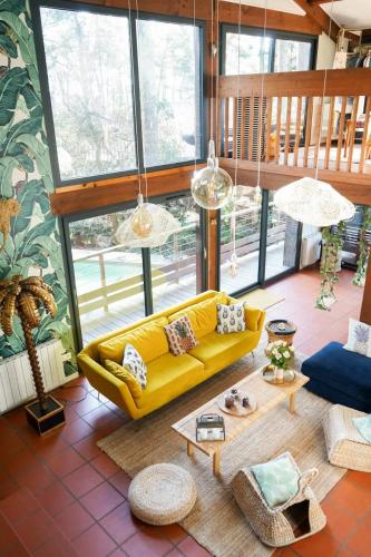 - un salon avec un canapé jaune et quelques fenêtres dans l'établissement La Villa Tropicool, à Lège-Cap-Ferret