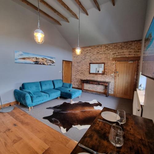a living room with a blue couch and a brick wall at Two Bedroomed Loft Apartment - The Old Drill Hall Ryde in Ryde