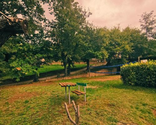 a bench in a park with trees and a fence at Camping Lucherino in Monticello
