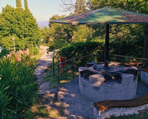 an outdoor grill with an umbrella on a path at Camping Lucherino in Monticello