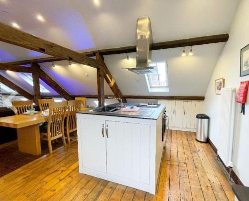 a kitchen with white cabinets and a dining room with a table at Seaside loft whitby abbey views with parking in Whitby