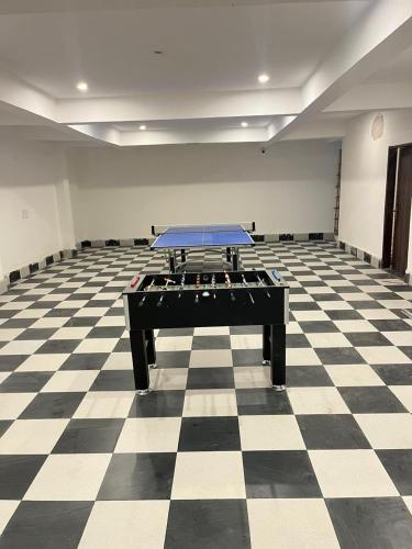 a room with a ping pong table on a checkered floor at Apna Homes Stay & Hotel I Gurugram I Sector-71 in Gurgaon